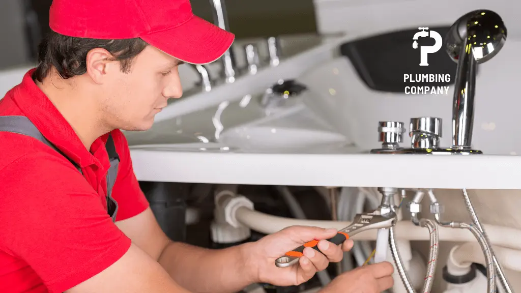 plumber installing garbage disposal unit in kitchen 