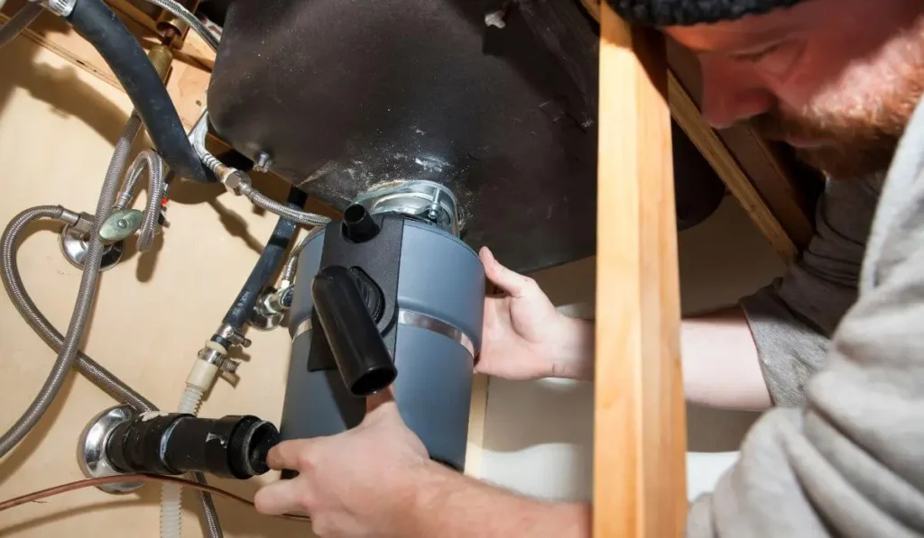 man aligning and adjusting garbage disposal under sink