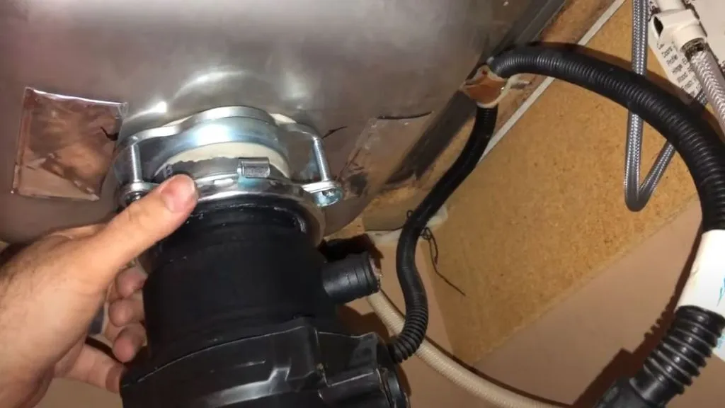 man removing old garbage disposal from flange assembly